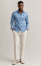 Load image into Gallery viewer, Man wearing a blue floral shirt and white pants against a plain background