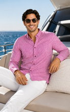Load image into Gallery viewer, A man wearing a textured pink long-sleeve button-up shirt and white trousers sits on a yacht lounge chair with the ocean in the background.