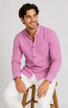 Load image into Gallery viewer, A man wearing a textured pink long-sleeve button-down shirt and white trousers, sitting on a wooden stool against a light gray background.